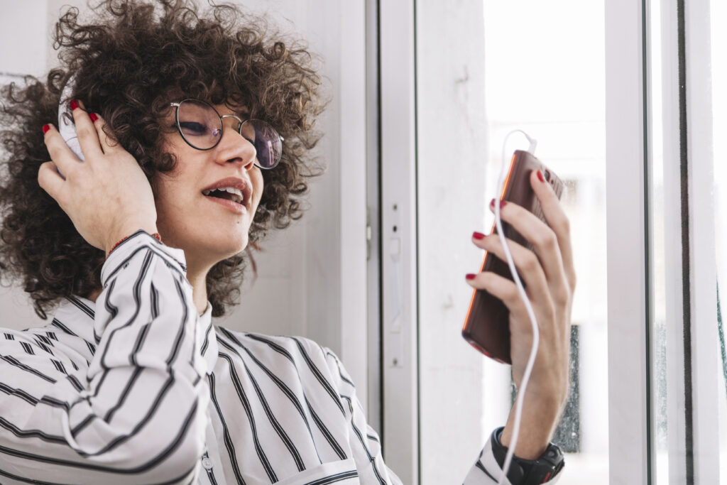 Menina tirando tensão ao cantar através de exercícios no celular.